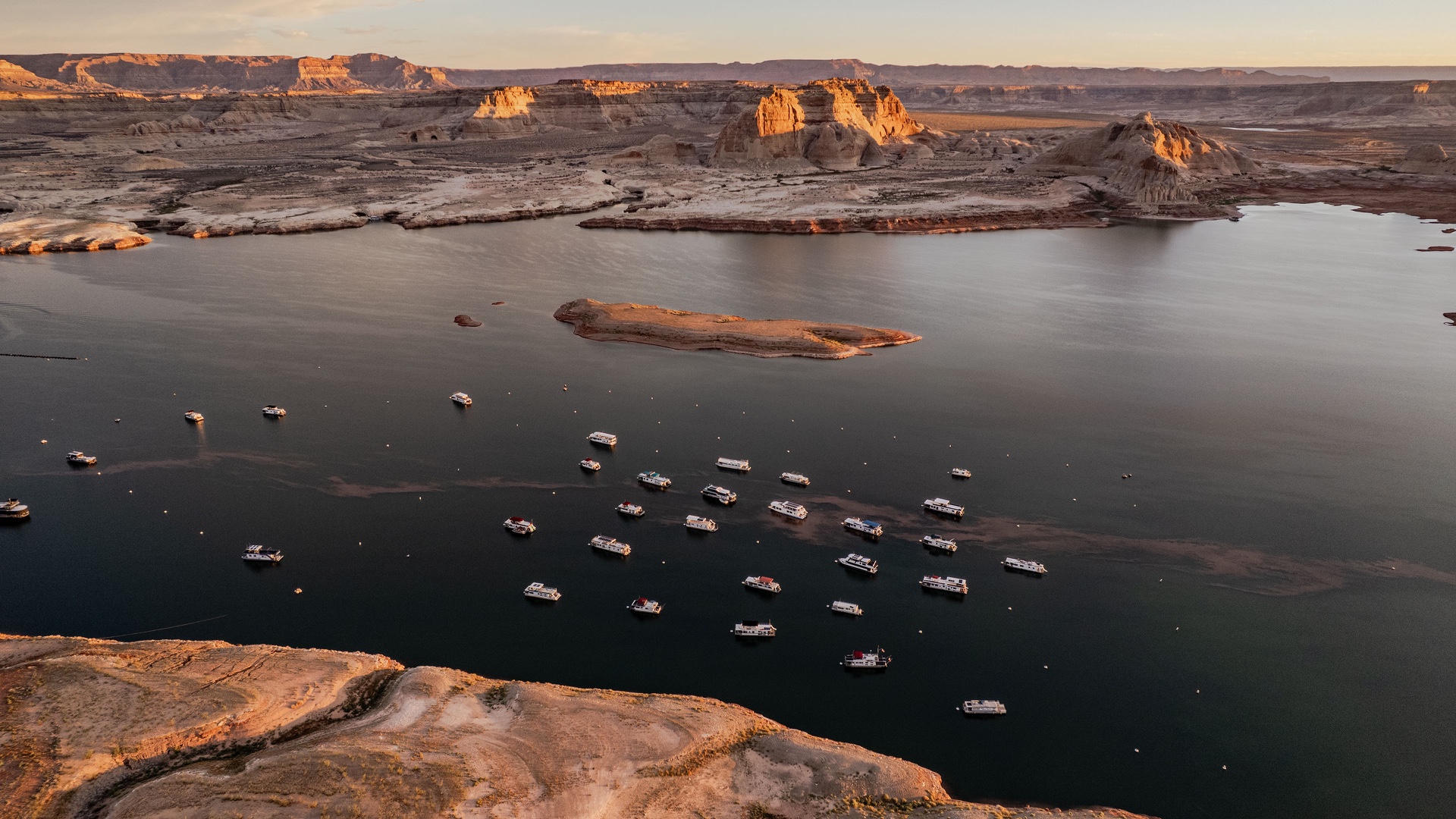 Boats beneath sunlit Lake Powell sandstone near Wahweap Marina
